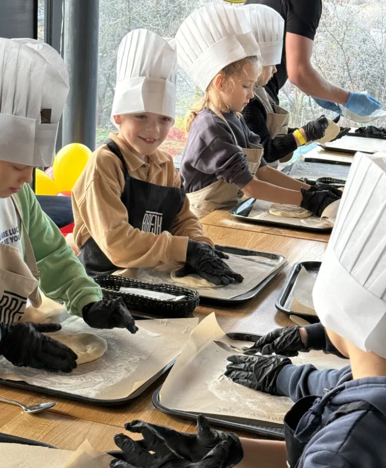 dzieci w&nbsp;czapkach kucharskich przy stole
